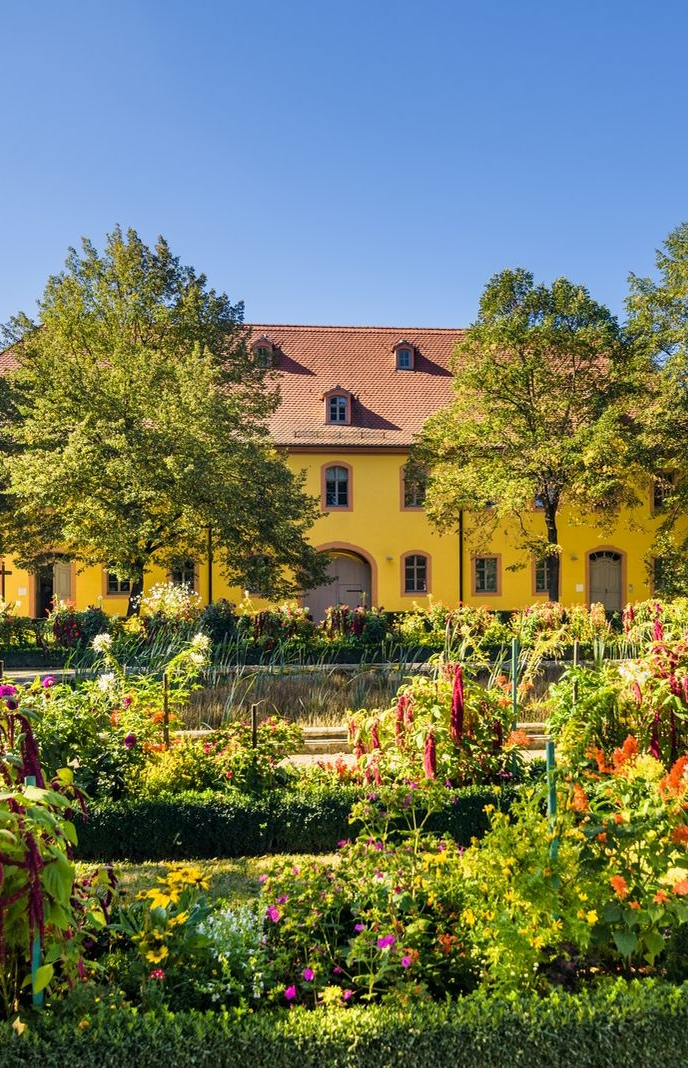 Ein historisches Gebäude mit sommerlich blühenden Garten 