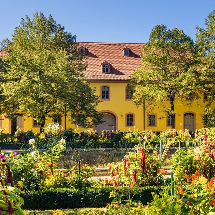 Ein historisches Gebäude mit sommerlich blühenden Garten 